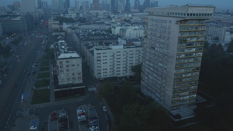 Forwards fly above urban neighbourhood before sunrise. Tilt up reveal cityscape with modern high rise buildings. Warsaw, Poland