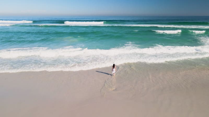 Aerial view of woman standing on white beach, Cape Town, South Africa.