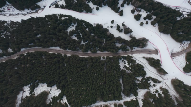 Cars driving on the alpine road under skiers on the ski track