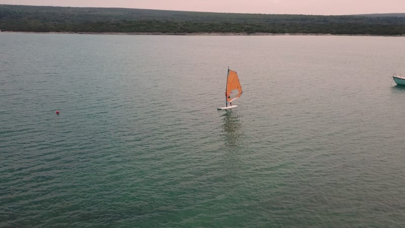 Aerial view of man practicing kitesurfing at transparent water.