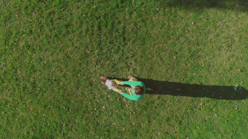 Aerial view of father rotating infant son at public playground.