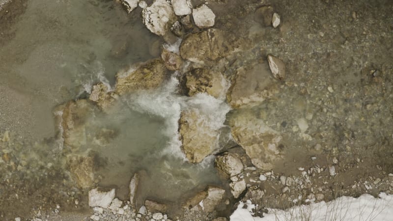 Ascending above a cold melt water stream in the snowy mountains