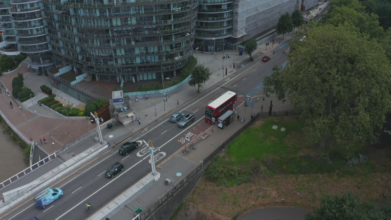 Aerial view of road in modern residential district. Rounded apartment complex. Red double decker standing on bus stop. London, UK