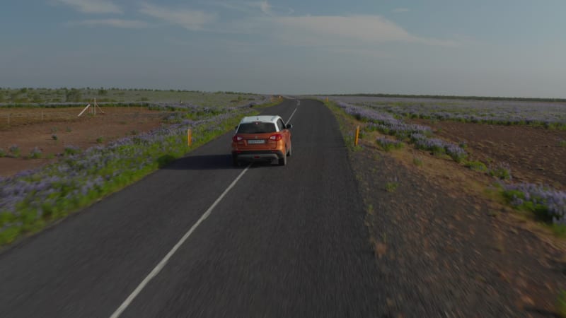 Drone view travelling by car discovering iceland driving on Ring Road. Aerial view off road car sightseeing iceland travelling by car on flowery countryside