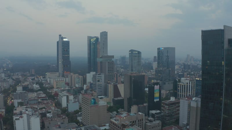 Ascending footage of group of downtown skyscrapers. Aerial view of tall office buildings and morning cityscape in background. Mexico City, Mexico.