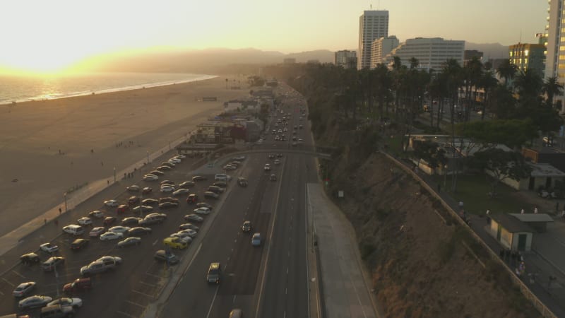 Famous Bridge overpass over Pacific Coast Highway by Santa Monica Beach in Los Angeles with light traffic in beautiful golden hour Sunset vibe, Aerial Dolly forward, Wide angle shot