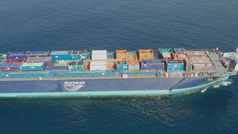 Cargo Ship loaded with colourful Containers and large crates cruising at sea