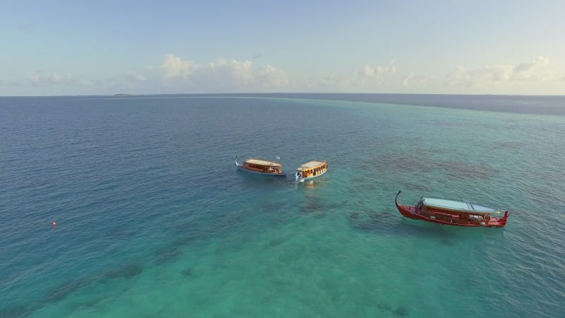 Aerial view above of luxury resort surrounded by transparent water.