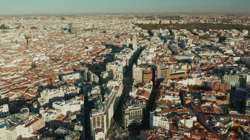 Fly above large city. Gran Via shopping and entertaining street surrounded with tall buildings. Panoramic aerial view of town.