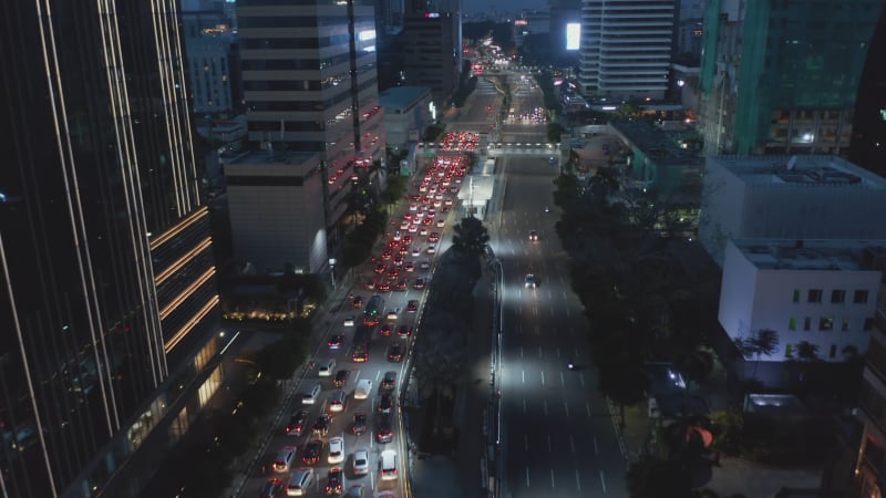 Aerial dolly shot of cars merging into a multi lane stopped traffic at a traffic light in urban city center