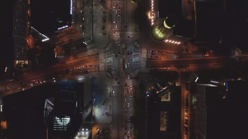 Aerial birds eye overhead top down panning view of cars starting at intersection on green light. Traffic in night city. Warsaw, Poland