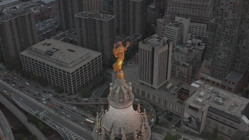 Circling golden statue in New York City with highway traffic and busy City