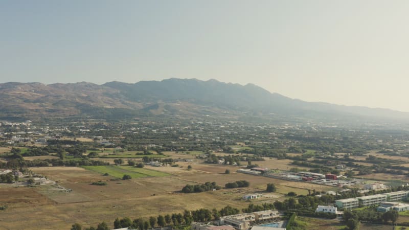 Aerial pan of houses at foot of mountain range