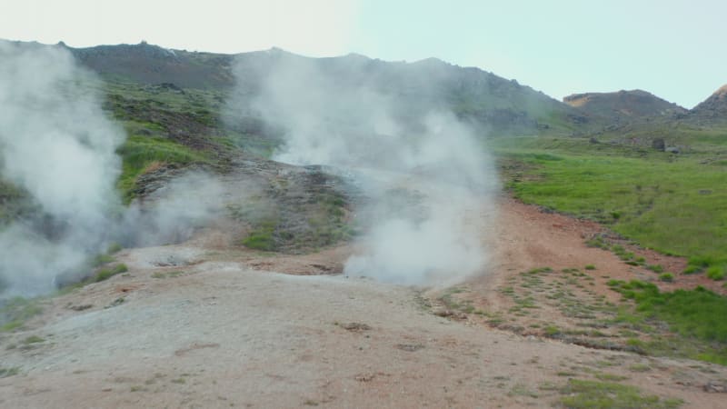 Drone view of steaming geothermal hot water craters in Iceland. Aerial view of amazing geothermal landscape with tourist exploring wilderness