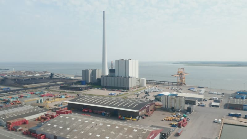 Aerial view slow rotation over the city of Esbjerg with his harbor and the Steelcon chimney of the coal and oil fueled power station. This chimney is the tallest in all Scandinavia