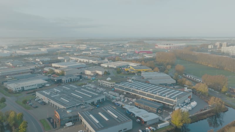 Fliegen Sie bei bewölktem Sonnenaufgang über ein Industriegebiet, eine stark befahrene Straße und ein Fußballstadion in der Nähe von Alkmaar, Niederlande