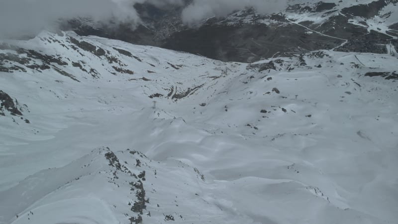 Aerial shot tilting up over ski slope revealing Val Thorens Village