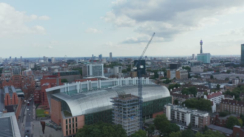 Orbit shot around tower crane on construction site. Modern building of Francis Crick Institute. London, UK