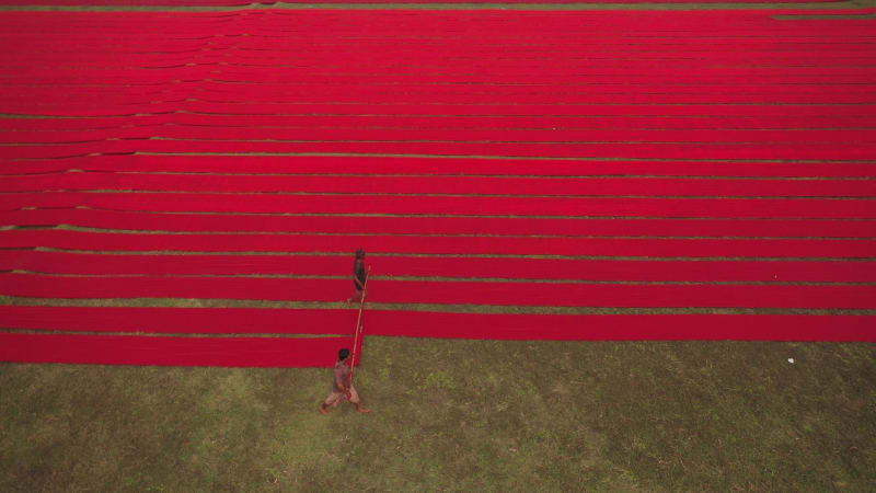 Aerial view of a man walking along red long textile stripes, Bangladesh.