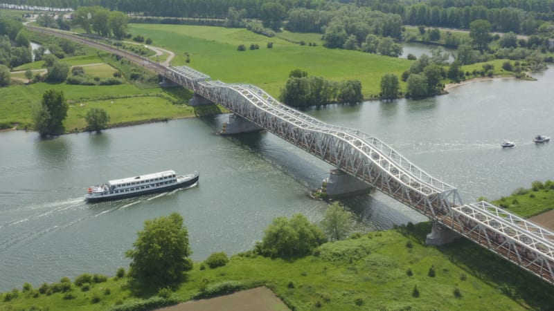 Flussfähre, die unter der Eisenbahnbrücke vorbeifährt