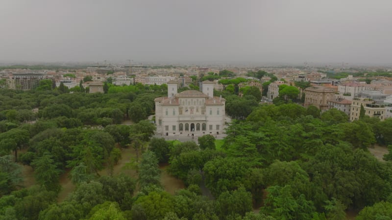 Aerial slide and pan footage of standalone historic villa in park, museum and Galleria Borghese. Rome, Italy