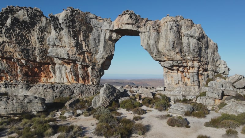 Aerial einer Frau in roter Jacke beim Wandern am Wolfberg Arch, Westkap, Südafrika.