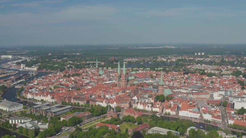 Aerial panoramic view of medieval city centre lined with Trave river. Holsten Gate, St. Marys, St. Peters and St. Jacobs churches. Luebeck, Schleswig-Holstein, Germany