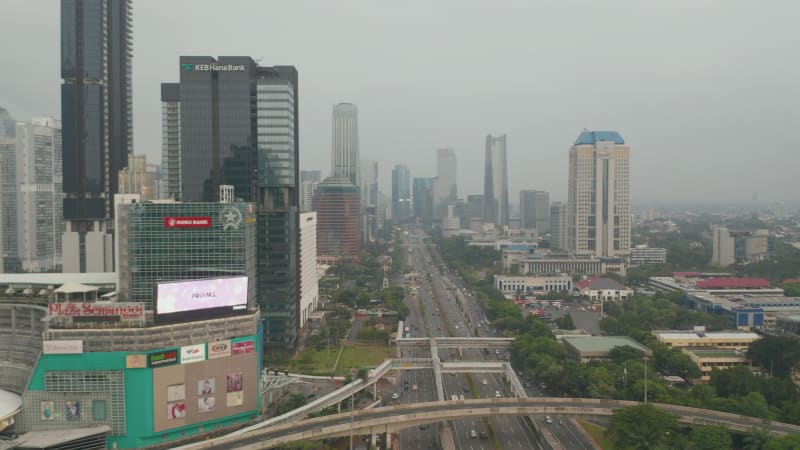 Aerial dolly wide view of busy multiple multi lane roads through modern city center with skyscrapers in Jakarta