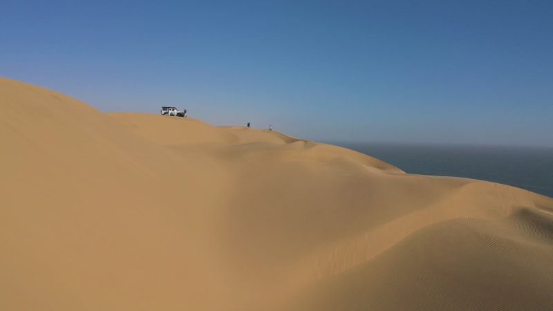 Aerial von Menschen mit einem Auto auf einer Sanddüne in der Wüste, Namibia.