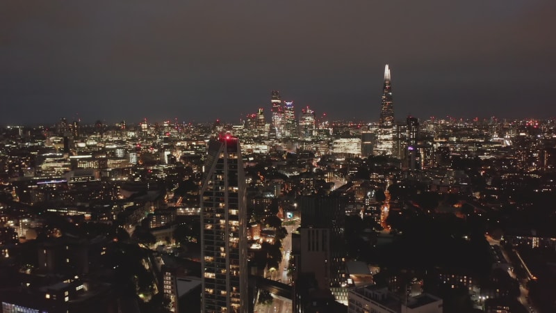 Absteigende und nach oben geneigte Aufnahme der nächtlichen Skyline. Panoramablick auf das Stadtbild mit einer Gruppe von Wolkenkratzern im Geschäftszentrum der Stadt. London, Großbritannien