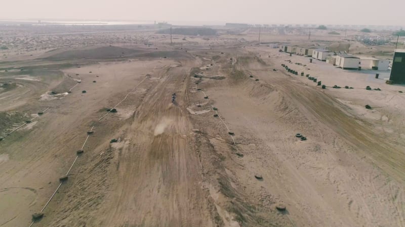 Aerial view of man practicing circuit motocross at desert landscape.