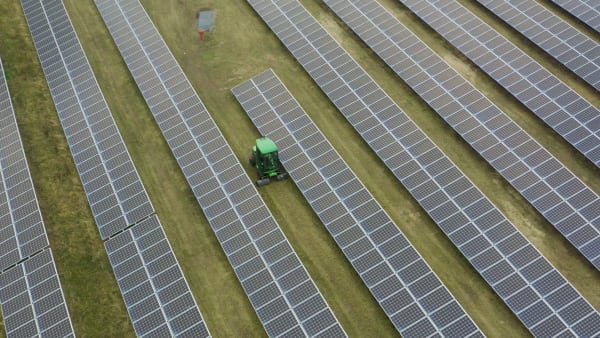 Solar energy farm with vehicle mowing the grass