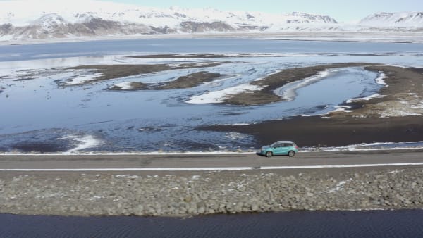 Car Driving Along a Narrow Road Over a Lake in Winter Conditions