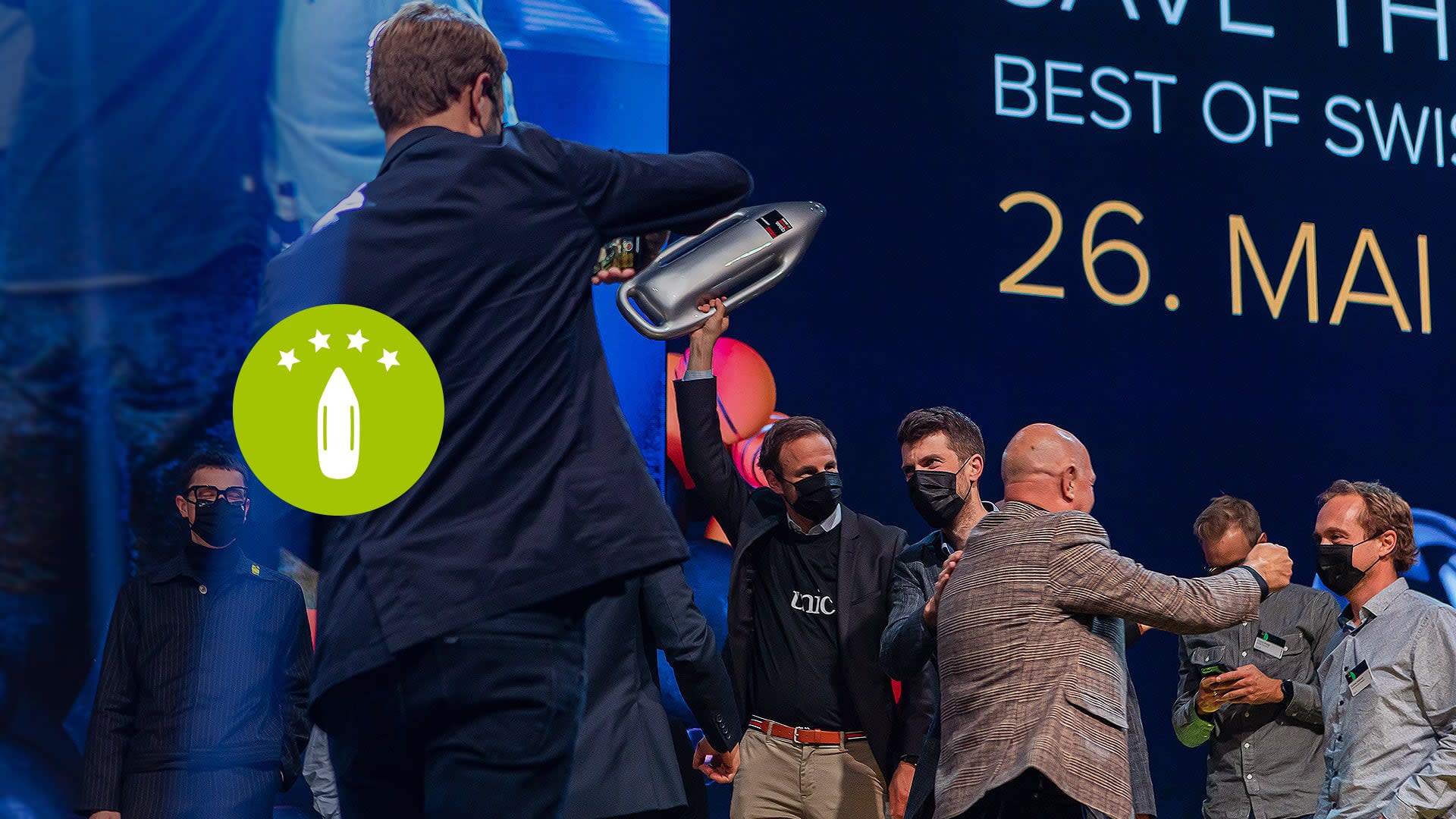 The picture shows the winners of Unic during the Best of Swiss Web event - a man holds up the prize, a silver buoy.