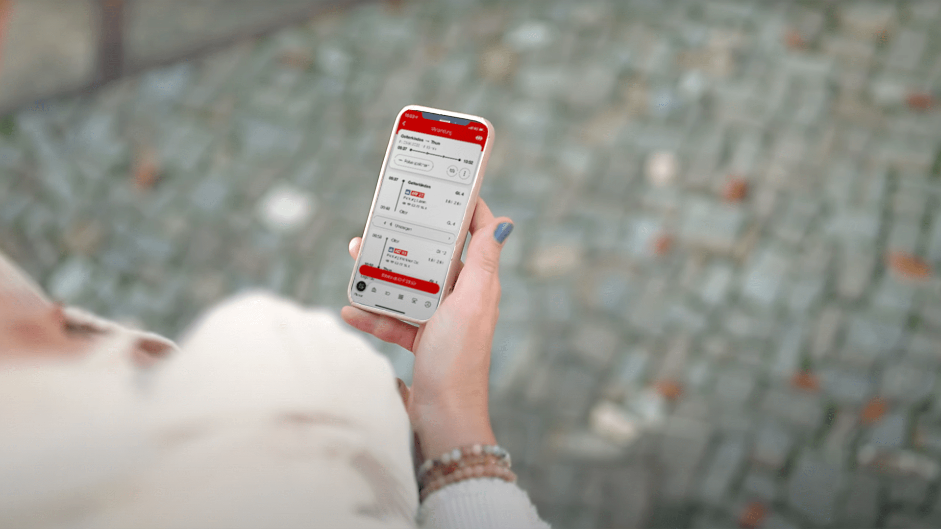 Das Bild zeigt eine Frau mit einem Smartphone. Auf dem Gerät ist die mobile App der SBB zu erkennen.