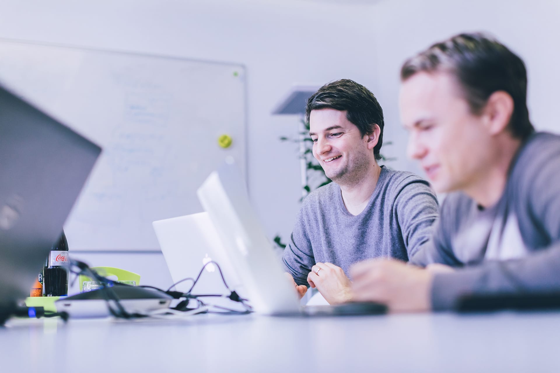 Zwei Männer sitzen nebeneinander und arbeiten an Laptops