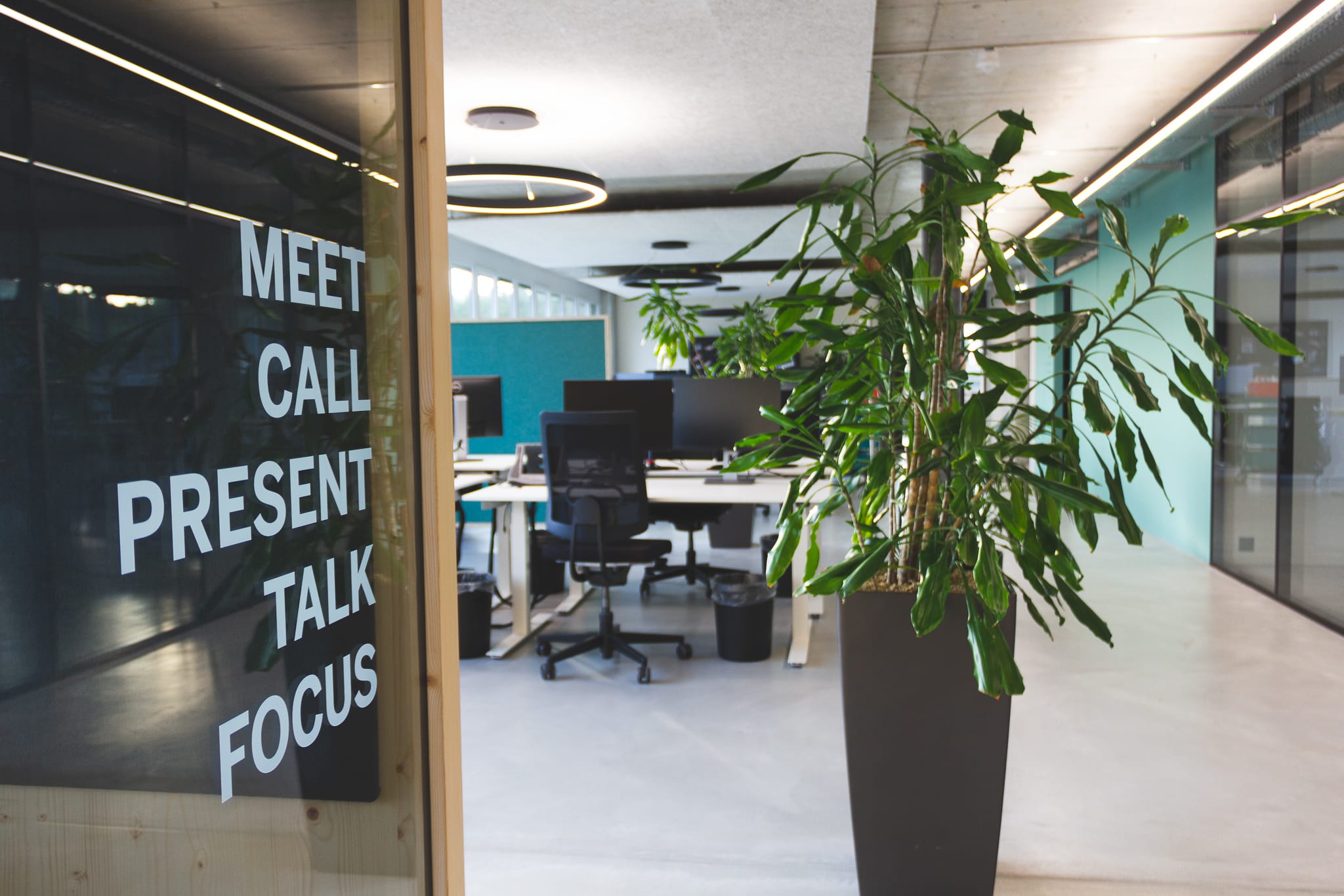 View of an open-plan office: Office chairs can be seen in the background and a meeting room in the foreground.