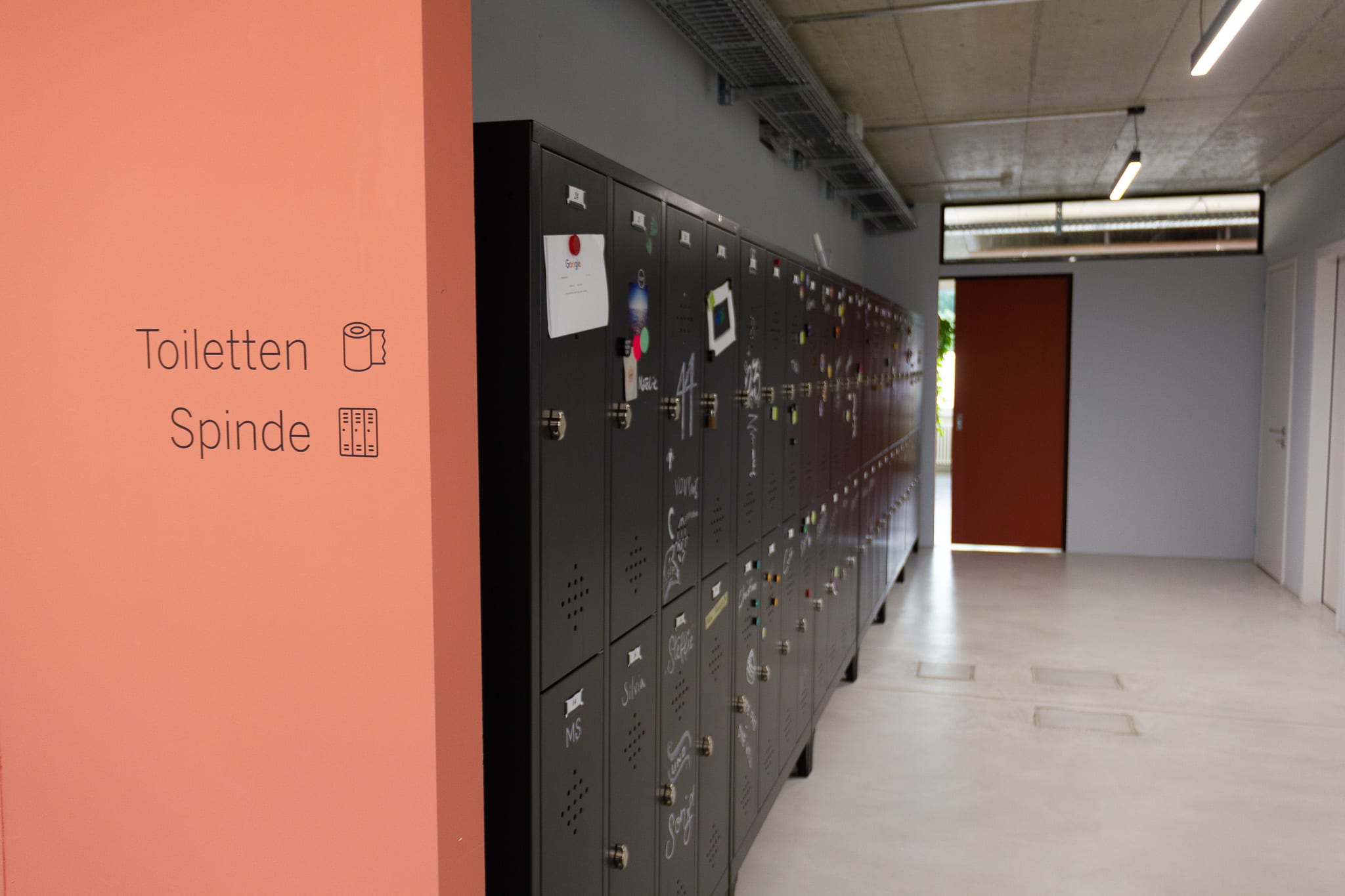 The picture shows a row of lockers and a toilet sign on the wall.