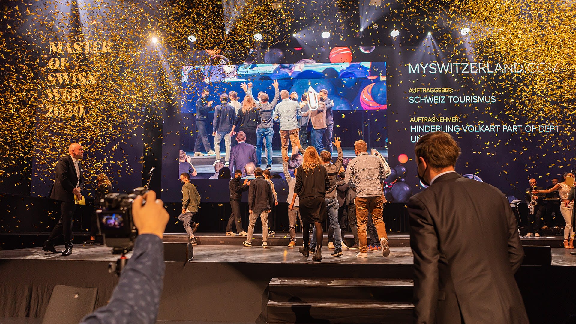 The picture shows the stage of the Best of Swiss Web Awards - tinsel can be seen falling onto the stage. The picture radiates a good atmosphere.