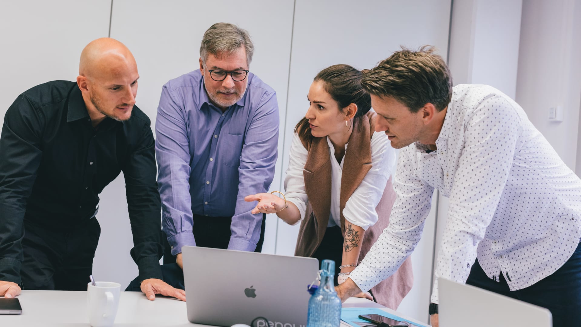 The picture shows the cooperation between CSS Krankenkasse and Unic. You can recognise 4 people, one of whom is a woman, standing in front of a notebook and discussing matters.