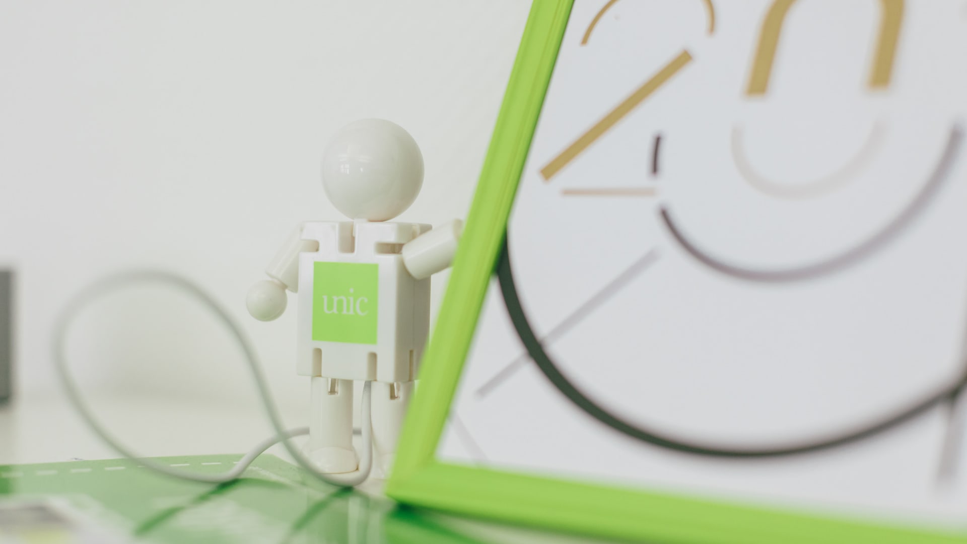 A robot with the Unic logo on the front next to an unidentifiable image with a green frame