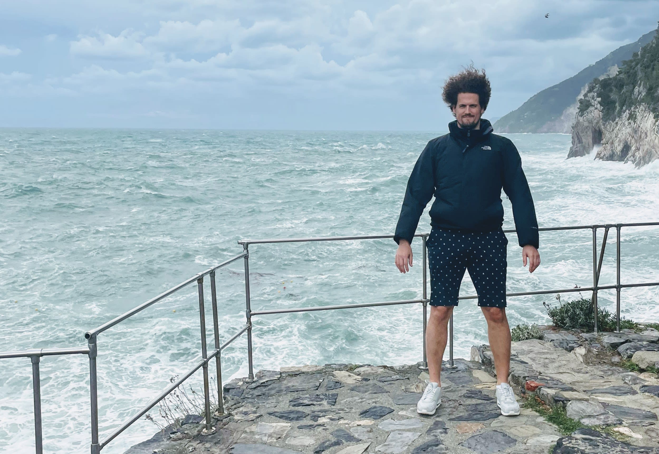 Mitarbeiter Benjamin auf einem Felssprung mitten im stürmischen Meer.