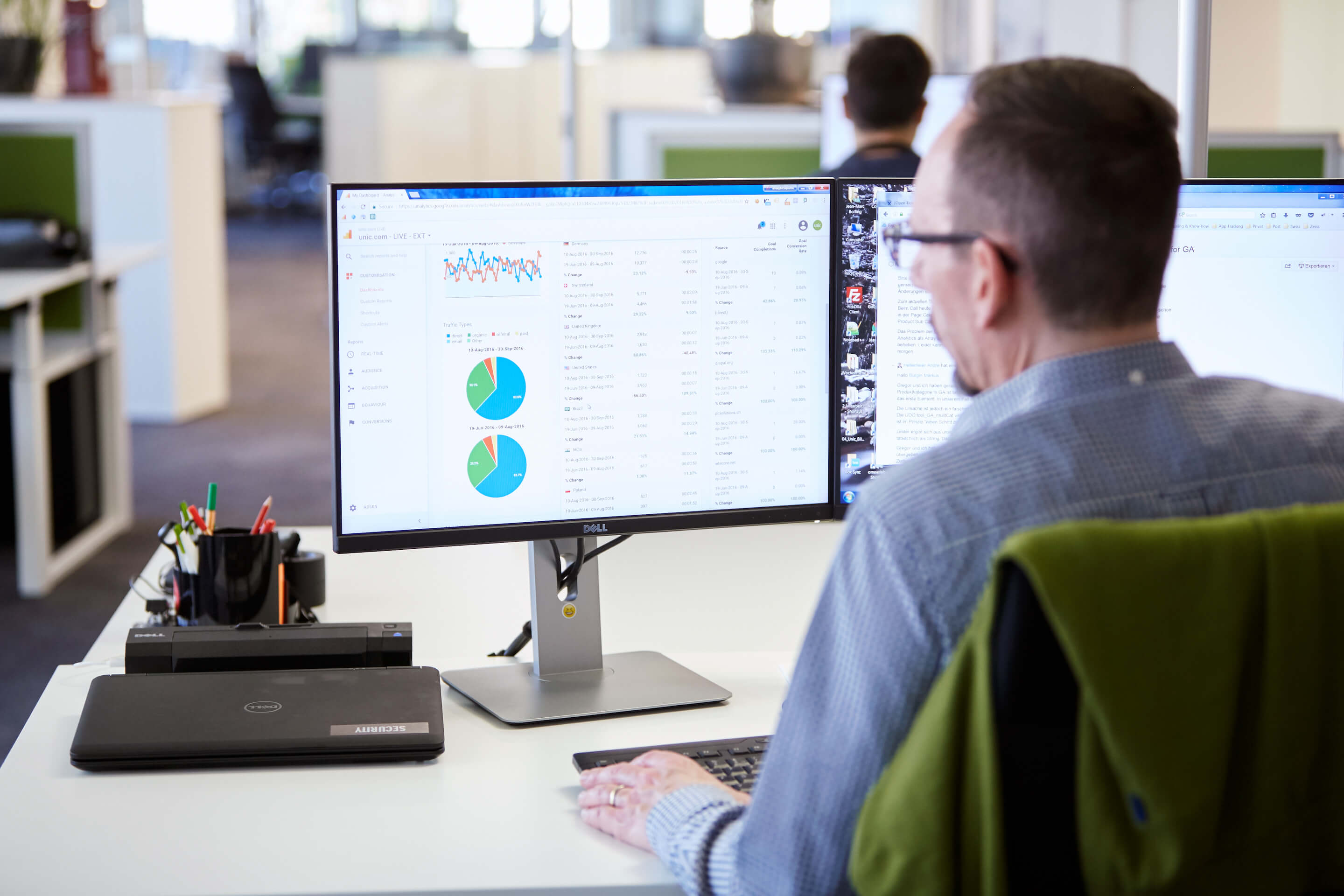 The picture shows a man studying a technical SEO analysis. KPIs and graphics can be seen on the screen in front of him.