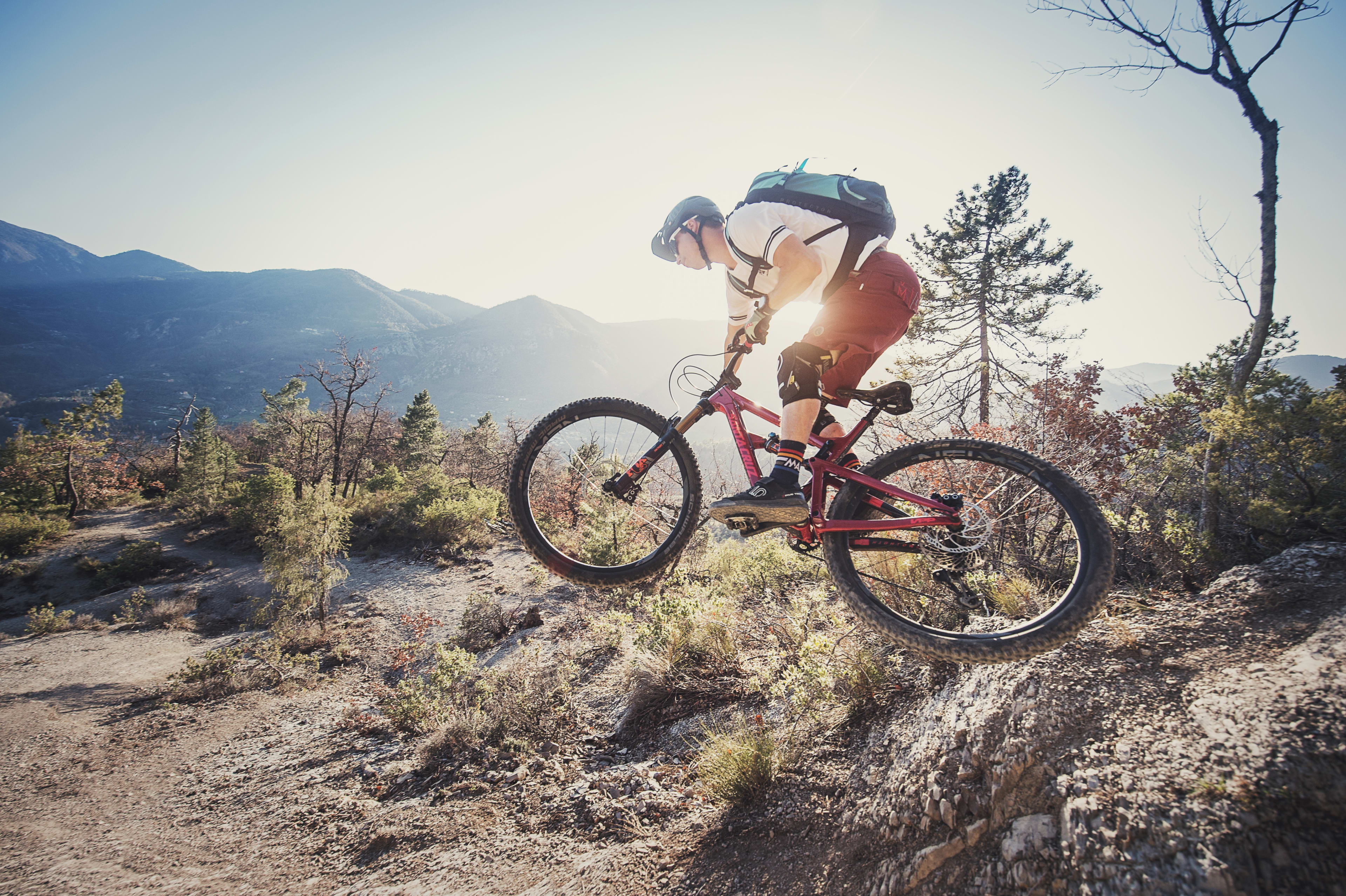 Mountainbike-Fahrer setzt zum Bunny Hop an und hebt aufm Trail ab.