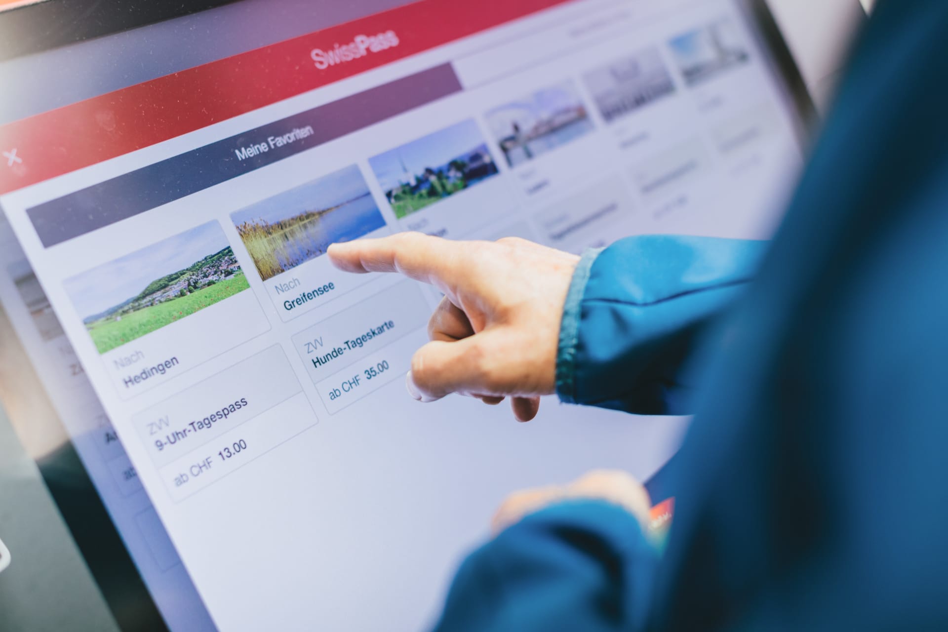 The picture shows an SBB ticket machine with the front end developed by Unic. A person is selecting their destination.