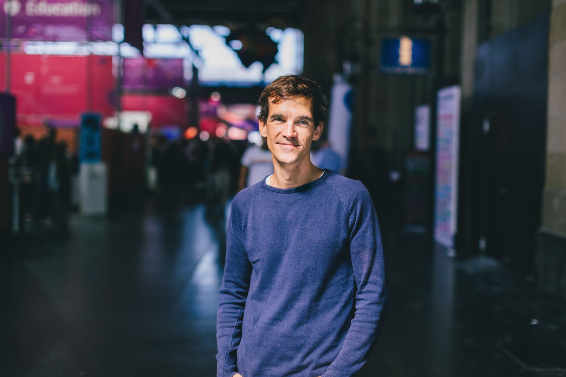 The picture shows Yves Tscherry, Senior Frontend Engineer at Unic. A large hall can be seen in the background.