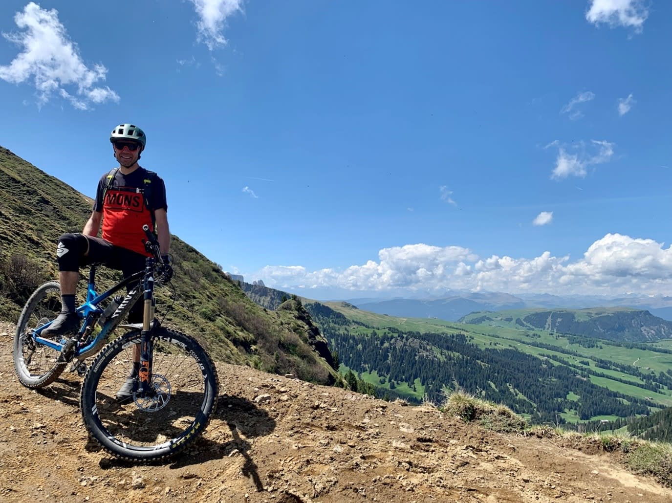 The picture shows a man on a mountain bike - not riding. A valley and other mountain ranges can be seen in the background.