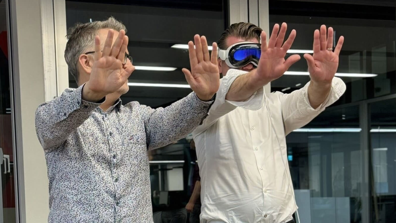 Ivo Bättig and Gerrit Taaks with outstretched hands to calibrate the Apple Vision Pro. Gerrit on the right is wearing the VR glasses.