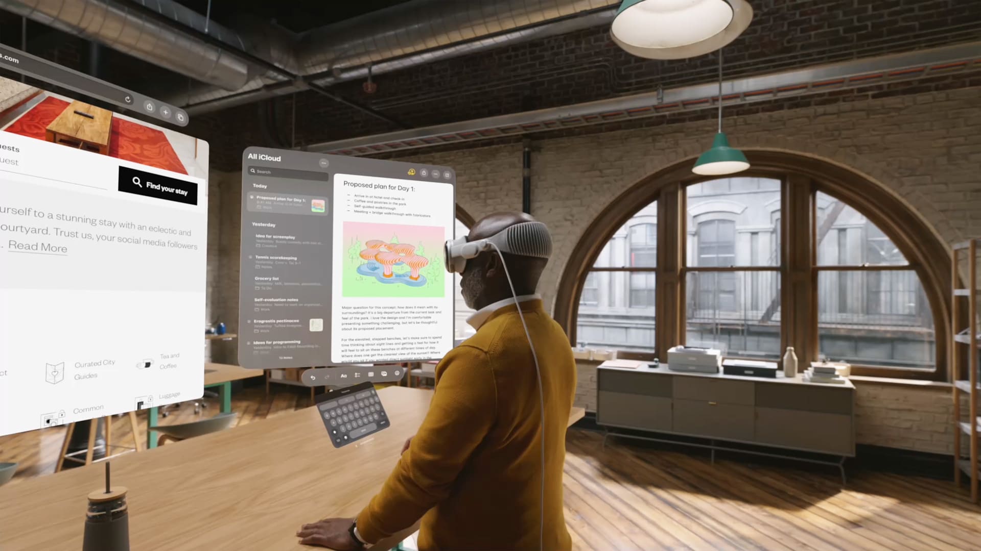 The picture shows the virtual world of Apple's Vision Pro. A man is standing with it in front of several screens. The recognisable office is also visualised.