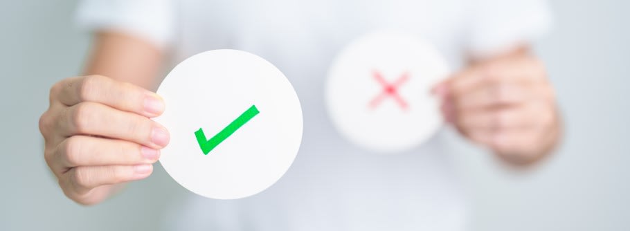 An image of a student holding a sheet with a tick and a cross on it